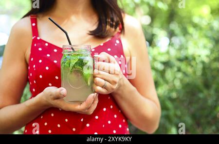 Junge brünette Frau mit einem marmeladenglas in ihrer Hand mit einem Mojito. Sommer trinken Konzept Stockfoto