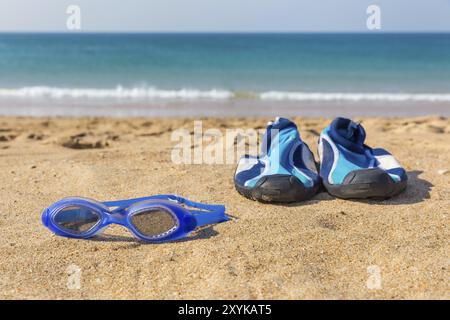 Blue Schwimmbrille und Wasser Schuhe an der Küste mit Meerblick Stockfoto