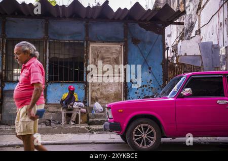 Havanna, Kuba am 23. Dezember 2015: ein Mann geht auf eine Straße in Centro Habana mit seinem Hemd Farbe von rosa Oldtimer Stockfoto