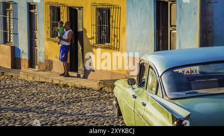 Trinidad, Kuba am 30. Dezember 2015: Kubanischer Vater mit Sohn neben dem Taxi im Morgenlicht Stockfoto