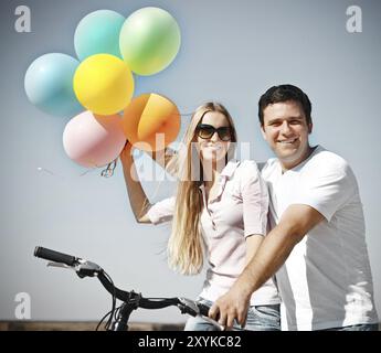 Glücklich lächelnd paar mit Luftballons auf dem Fahrrad in Sommertag Stockfoto