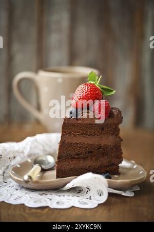 Stück Schokolade Kuchen mit Zuckerguss und frischen Beeren auf hölzernen Hintergrund Stockfoto