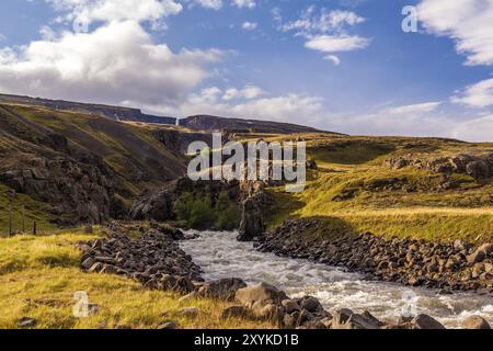 Weißer Fluss, der durch vulkanisches Gestein bei Hengifoss in Island fließt Stockfoto