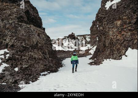 Junge erkunden Sie den schneebedeckten, felsigen schwarzen Strand Djúpalónssandur Island. Stockfoto