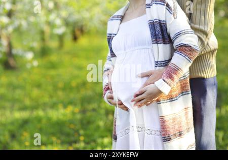 Glücklich schwanger paar im Garten blühen. Nahaufnahme Stockfoto