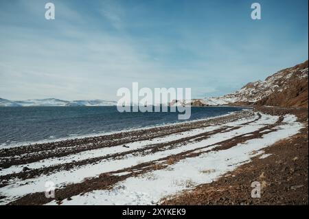 Schneebedeckter schwarzer Strand Djúpalónssandur Meer und blauer Himmel in Island Stockfoto