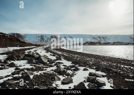 Schneebedeckter schwarzer Strand Djúpalónssandur Meer und blauer Himmel in Island. Stockfoto