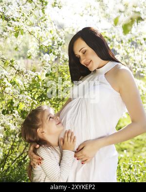 Glückliche schwangere Mutter und ihre kleine Tochter in den Frühling Stockfoto