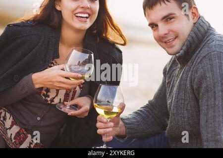 Junge glückliche Paar Picknick mit Weißwein am Strand zusammen. Nahaufnahme Stockfoto