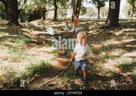 Wilde Kinder, die im Sommer mit Stöcken am Bach spielen Stockfoto