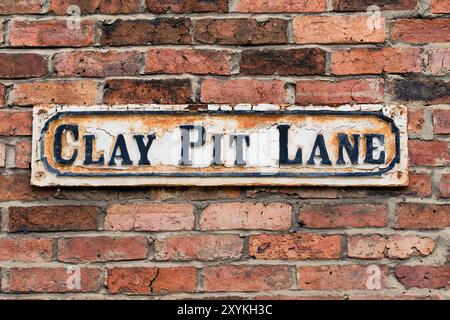 Leeds England: 4. Juni 2024: Ein verwittertes Straßenschild Clay Pit Lane, das an einer alten Ziegelmauer in der Nähe der Leeds First Direct Arena angebracht wurde Stockfoto