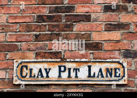 Leeds England: 4. Juni 2024: Ein verwittertes Straßenschild Clay Pit Lane, das an einer alten Ziegelmauer in der Nähe der Leeds Arena angebracht wurde. Mit Kopierbereich Stockfoto