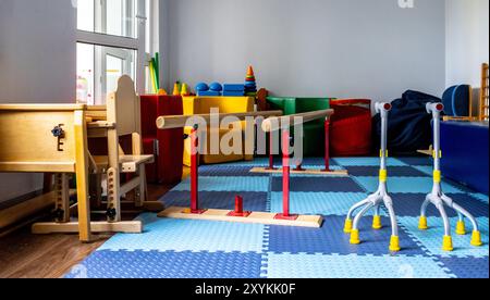 Farbenfrohe Rehabilitationsgeräte sind in einem für körperliche Rehabilitationsübungen konzipierten Kindertherapieraum angeordnet. Stockfoto