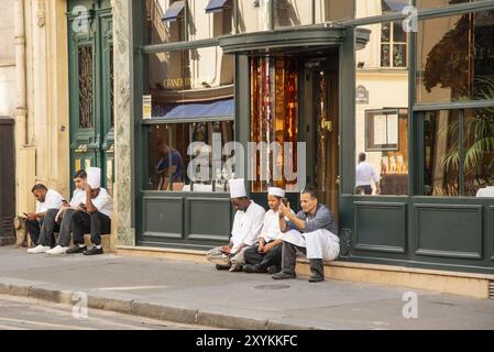 Paris, Frankreich. August 2022. Köche und Kellner entspannen sich auf dem Bürgersteig vor einem Restaurant in Paris Stockfoto