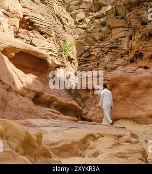 Ein Mann in weißer arabischer Kleidung läuft in einem farbigen Canyon Stockfoto