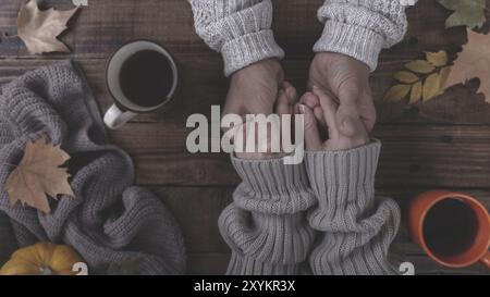 Paar in Liebe Hände halten und trinken Kaffee mit Herbstlaub bedeckt Stockfoto