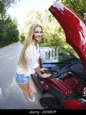 Frau stand in der Nähe der geöffneten Motorhaube des gebrochenen Cabriolet und auf Hilfe warten Stockfoto