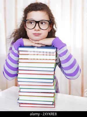 Kleine Brünette mit einem Haufen Bücher Stockfoto