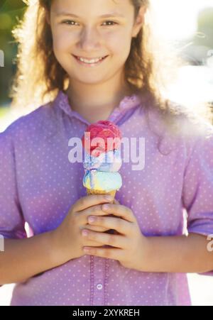 Kleines lächelndes Mädchen, das draußen Eisbecher in den Händen hält Stockfoto