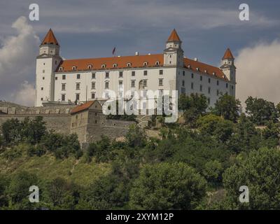 Ein beeindruckendes Schloss mit weißer Fassade und roten Türmen auf einem Hügel unter blauem Himmel, Bratislava, Slowakei, Europa Stockfoto