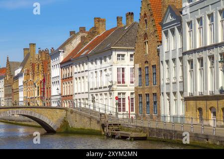 Brügge, Belgien, Panoramablick auf die Straße mit Kanal und farbenfrohen traditionellen Häusern vor blauem Himmel in einem beliebten belgischen Reiseziel Stockfoto