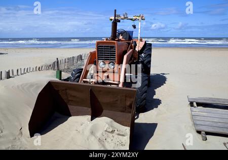 Alter roter Traktor am Strand in der Nähe des Meeres Stockfoto