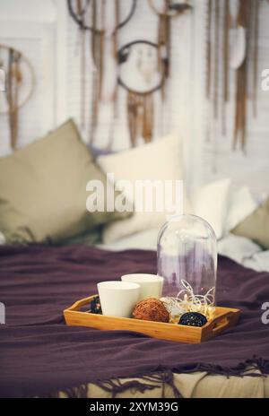 Zwei weiße Tassen auf einem Tablett auf dem Bett in Boho style, romantische Konzept Stockfoto