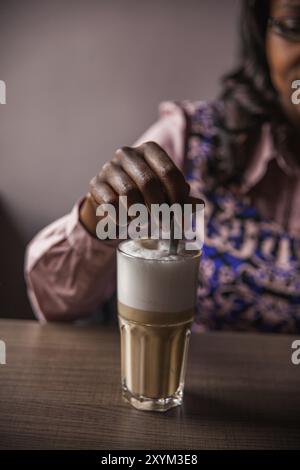 Frau rührt heißen Latte mit einem Löffel Stockfoto