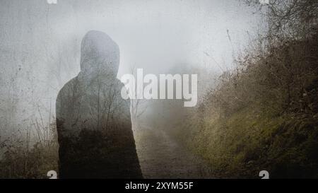 Eine doppelte Exposition einer geisterhaften Kapuzenfigur. Im Winter auf einem gruseligen Landweg stehen, mit einem Grunge-Schnitt Stockfoto