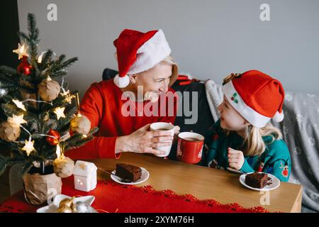 Mutter und Tochter genießen gemeinsam Weihnachtsgeschenke. Weihnachtsdesserts, festliches Essen, Familienbindung, Weihnachtsfeier, Süßigkeiten teilen, gemütlich Stockfoto