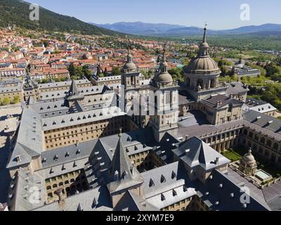 Nahaufnahme eines historischen Klosters mit Türmen, umgeben von einer Stadt und Bergen im Hintergrund, aus der Vogelperspektive, Real Sitio de San Lorenzo de El Escor Stockfoto