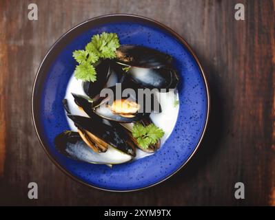 Blick auf die blaue Schüssel mit köstlicher Suppe mit Garnelen und Muscheln auf dem Holztisch im Restaurant Stockfoto