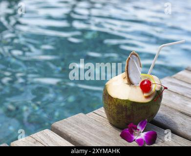 Kokosnuss mit Strohhalm zu trinken, am Swimmingpool cocktail Stockfoto