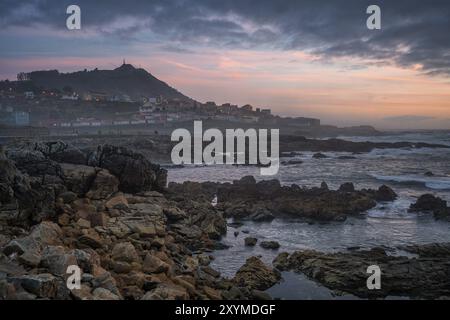 Ein Guarda schöne Meereslandschaft Felsstrand mit Stadt im Vordergrund bei Sonnenuntergang, in Spanien Stockfoto