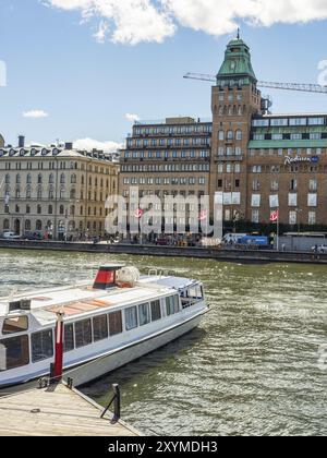 Stadtszene mit mehreren großen Gebäuden und Booten auf dem Wasser bei sonnigem Wetter, stockholm, ostsee, schweden, skandinavien Stockfoto