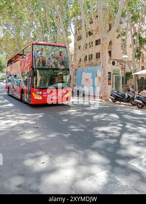 Palma de Mallorca, Spanien; 09. august 2024: Roter Touristenbus voller Touristen, der auf sonniger Summe durch das historische Zentrum von Palma de Mallorca schlendert Stockfoto