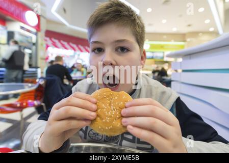 Teenager isst einen Hamburger und ein Cafe Stockfoto