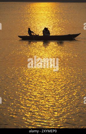 Silhouetten indischer Touristen machen eine Ruderbootfahrt bei Sonnenuntergang auf dem Ganges in Varanasi, Indien, Asien Stockfoto