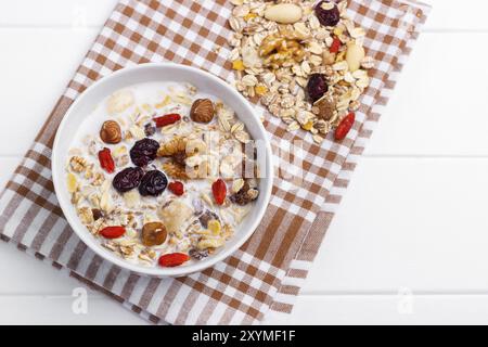 Schüssel hausgemachtes Müsli mit Nüssen, Beeren, getrockneten Früchten, Glas Milch und Honig. Gesundes Frühstück. Draufsicht Stockfoto