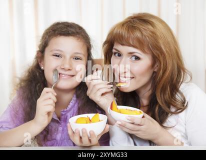 Glückliche Mutter und Tochter essen Müsli und Obst Stockfoto