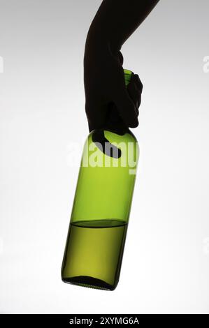 Silhouette einer Hand hält eine grüne Flasche Weine Stockfoto