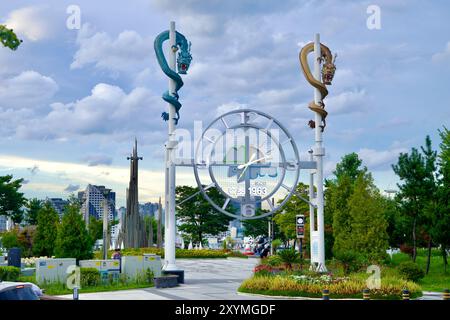 Sokcho, Südkorea - 28. Juli 2024: Am Eingang zum Cheongcho Lake Amusement Park befindet sich eine große Uhr, flankiert von goldenen und blauen Drachenskulpturen Stockfoto