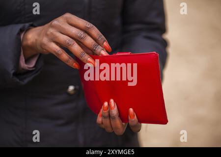 Die Frau hält die rote Brieftasche in der Hand Stockfoto