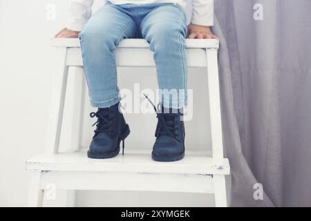 Stilvolles kleines Baby in Leder Schuhe auf dem Stuhl niedlich. Nahaufnahme Stockfoto