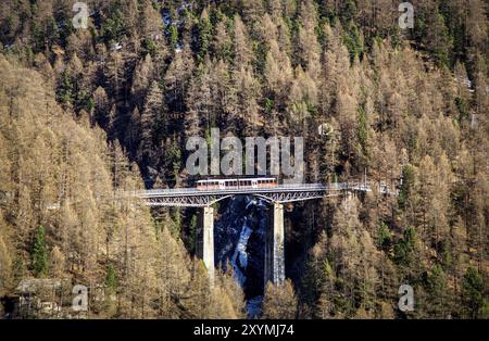 Zermatt, Schweiz, 11. April 2017: Ein roter Zug fährt über eine beeindruckende Brücke in Zermatt Stockfoto