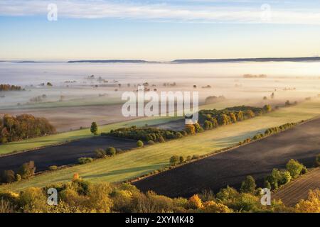 Panoramablick auf eine wunderschöne ländliche Landschaft mit Feldern und niedrigem Morgennebel bei Sonnenaufgang im Herbst Stockfoto