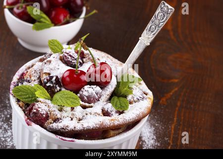 Französische Clafoutis mit Kirsche in Keramik Förmchen auf rustikalen Holztisch Stockfoto