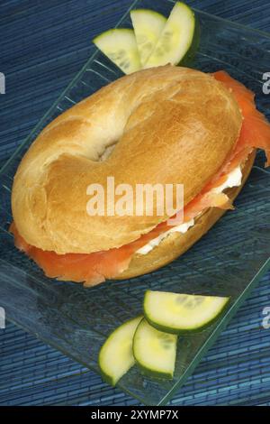 Bagel mit Weichkäse und Räucherlachs mit Gurkenscheiben auf einer durchsichtigen Glasschale serviert Stockfoto