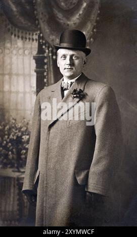 Vintage-Foto eines Mannes mit Derby-Hut und Mantel in einem Studio um 1920. Stockfoto