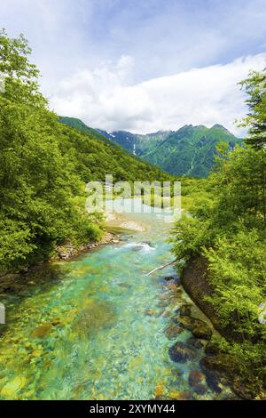 Das kristallklare Wasser des Flusses Azusa windet sich durch unberührten Wald mit Blick auf die Landschaft des Mount Hotaka-Dake im Hintergrund in der japanischen Alpenstadt Stockfoto